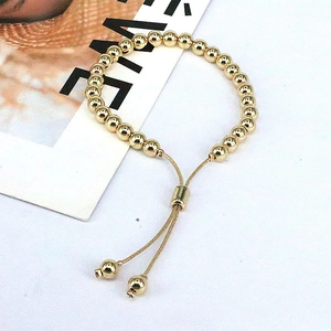 Polished golden beaded bracelet with adjustable pull-string clasp and ball pendants