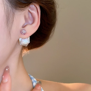 Detail of asymmetric cubic zirconia earrings with pink stud and iridescent crystal drop