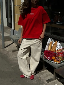 Stile street style all'aperto di una t-shirt in cotone rosso con pantaloni larghi bianchi
