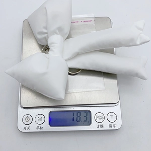Detailed view of white fabric bow keychain weighing 18.3g on a digital scale