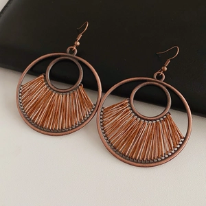 Detail of vintage bronze round earrings featuring brown woven fan-shaped patterns