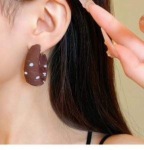 Close-up of vintage brown and white polka dot fabric wrapped C-shaped hoop earrings