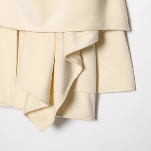 Close-up of cream wool coat fabric featuring elegant draped folds and soft cashmere texture