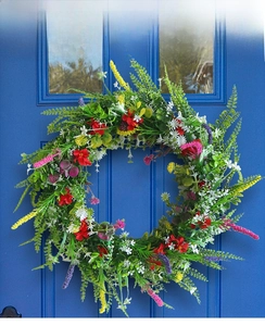 Primo piano di una ghirlanda di fiori selvatici colorati su una porta di legno blu scuro