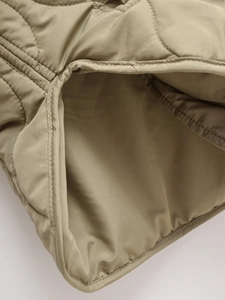 Close-up of quilted hooded coat detailing precise stitching and khaki nylon fabric texture