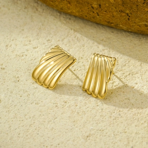 Golden rectangular stud earrings with shell texture on natural beige stone background