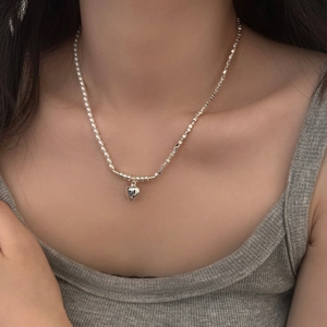 Close-up of heart pendant necklace with pearls and silver blocks on model neck