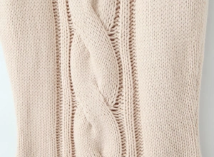Close-up of beige cable knit pattern showing premium thick texture of the dress