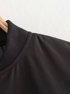 Gros plan détaillé du col côtelé et des coutures sur veste baseball noire femme