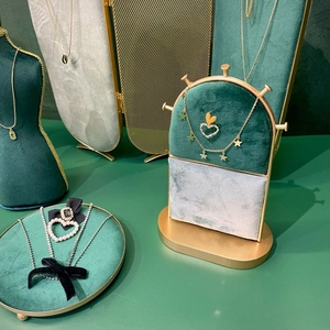 Golden necklace display with pearl heart, velvet bow, and stars on green velvet stand