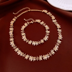 Macro detail of gold-plated rectangular zircon necklace and bracelet set on brown fabric