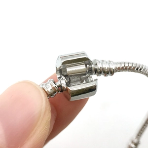 Macro detail of silver snake chain bracelet clasp mechanism on white background