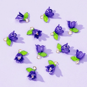 Macro view of purple flower charms with green leaves for DIY jewelry making