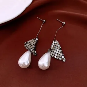 18k gold plated silver needle drop earrings with pearly teardrop on terracotta fabric