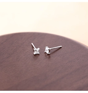 Macro shot of silver square zircon stud earrings with S925 hallmark on walnut wood surface