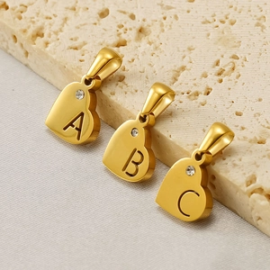 Goldener Herzanhänger mit Buchstabe und Diamant auf strukturiertem Steinuntergrund