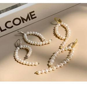 Detailed view of baroque pearl curved earrings in gold and silver finish on book