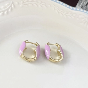 Gros plan de boucles d'oreilles fleur plaquées or et émail rose sur plat en céramique