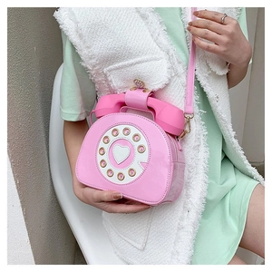 Close-up of pink retro telephone shaped crossbody bag with vintage rotary dial and heart detail