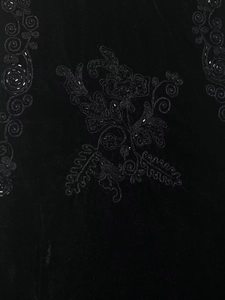 Close-up of intricate black velvet embroidery with delicate beadwork and shimmering sequins