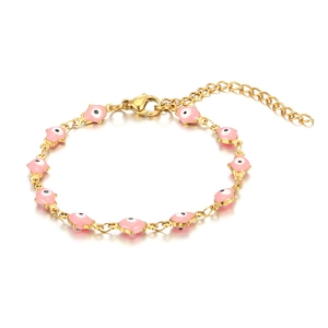 Detail of pink enamel Hamsa Hand and Evil Eye charms on a golden stainless steel bracelet