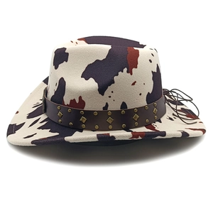 Detail view of cow print western cowboy hat with studded leather band and bronze rivets