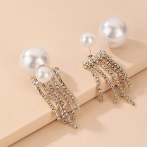 Macro shot of faux pearl earrings with long sparkling rhinestone tassels on gold chain