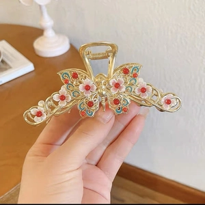 Detailed close-up of a butterfly hair claw with pink flowers and red bead accents
