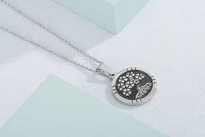 Detailed view of silver stainless steel tree of life pendant with black embossed pattern