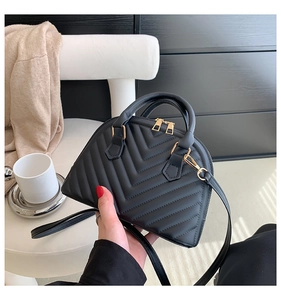 Detail of black V-quilted faux leather bag with elegant gold zipper and metal hardware