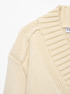 Detail of V-neck ribbed neckline and thick knit texture on a cream cardigan