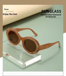 Detail of round oversized sunglasses with brown amber frame and colorful rhinestone accents