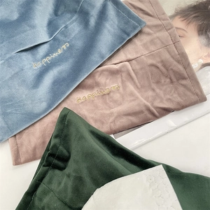 Detail of embroidered gold Happiness text on velvet tissue bags in blue, pink, and green