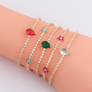 Five gold bracelets with colorful teardrop zircons on a model arm against white background