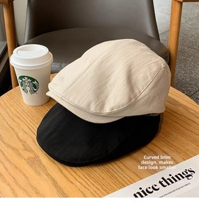 Detail of beige and black retro newsboy caps with curved brims on a wooden table