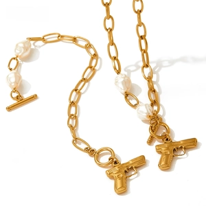 Detailed view of gold pearl necklace and bracelet set featuring pistol charms and toggle clasp