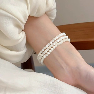 Detailed view of triple-layered 4mm faux pearl elastic bracelet on a female wrist