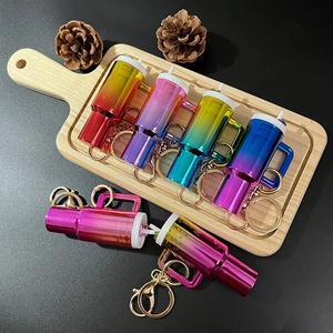 Close-up of six colorful gradient metal whistle keychains on a wooden display