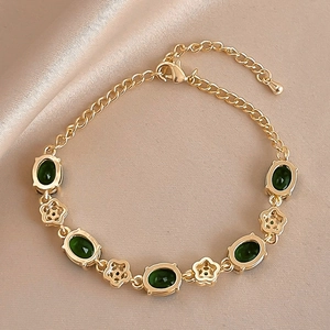 Vue détaillée d'un bracelet vintage doré avec pierres vertes ovales sur fond en soie