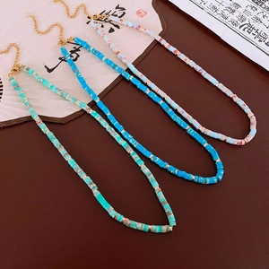 Close-up of three Shoushan stone necklaces with gold beads on a retro Chinese fan background