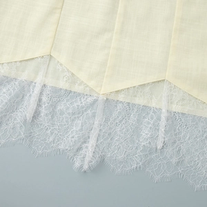 Gros plan de l'ourlet de robe en coton-lin beige avec dentelle de cils blanche délicate