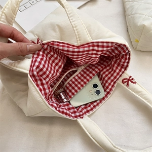 Detail of quilted canvas tote showing red bow embroidery and red gingham lining pocket