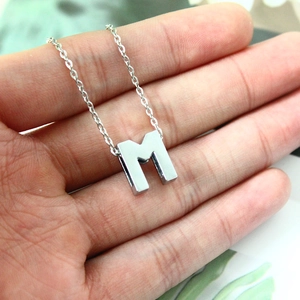 Macro detail of a polished silver 8mm rhinestone letter M charm on a hand