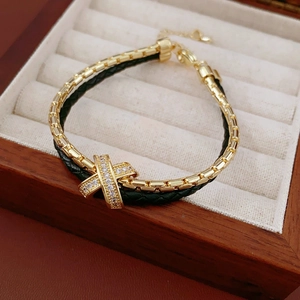 Detailed macro of gold plated double-layer bracelet with zircon X charm and green cord