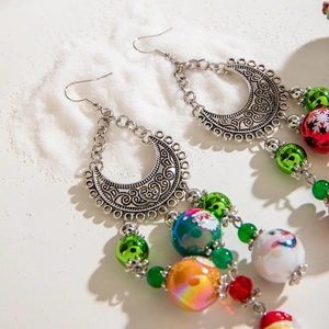 Detailed view of handmade beaded Christmas earrings with Santa and snowflake motifs
