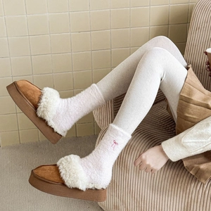 Close-up of plush mink fleece socks with embroidered pink bow detail and snow boots