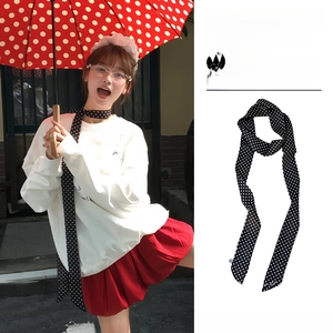 Vue macro d'un foulard étroit en soie à pois noirs et blancs de style français pour femme