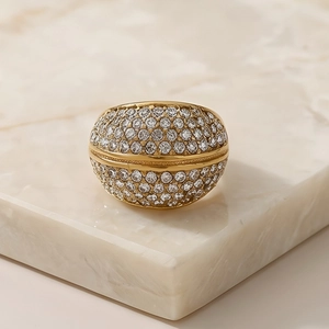 Macro detail of gold-plated dome ring with micro-paved sparkling crystals on stone base
