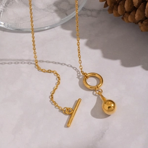 Golden OT clasp necklace with polished water drop pendant on a marble background