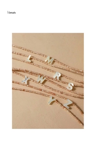 Macro shot of mother-of-pearl initial pendants on faceted pink beaded necklace chains